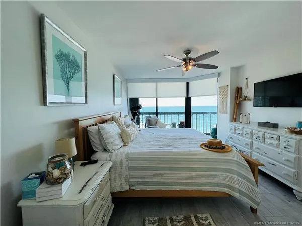 a view of a patio with a table and chairs under an umbrella with palm trees