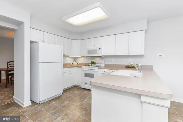 a kitchen with a sink a refrigerator and white cabinets
