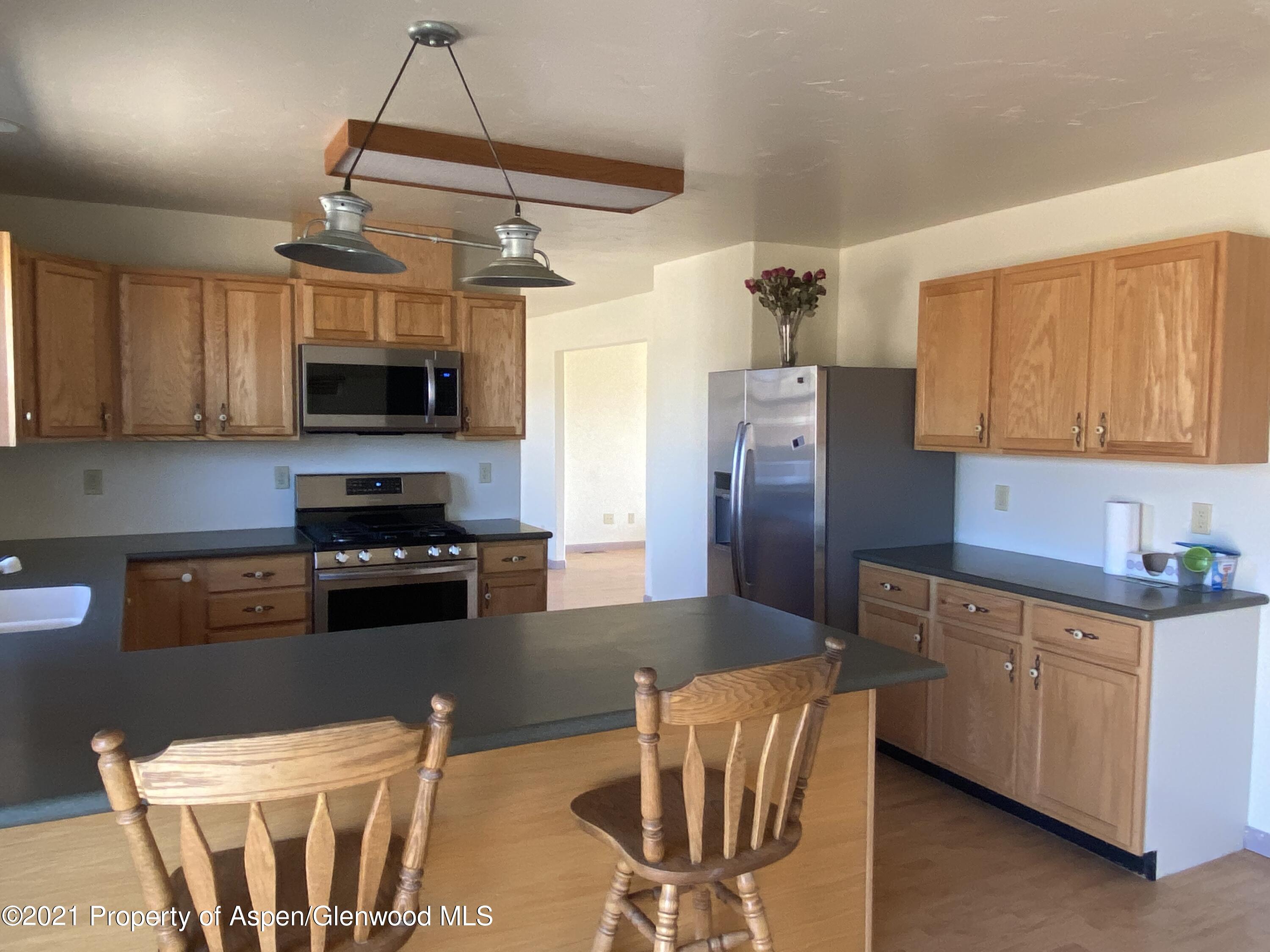 658 Cindys Way Rifle, CO 81650 - Photo 2 of 30 a kitchen with stainless steel appliances wooden cabinets a stove a sink a refrigerator and a microwave