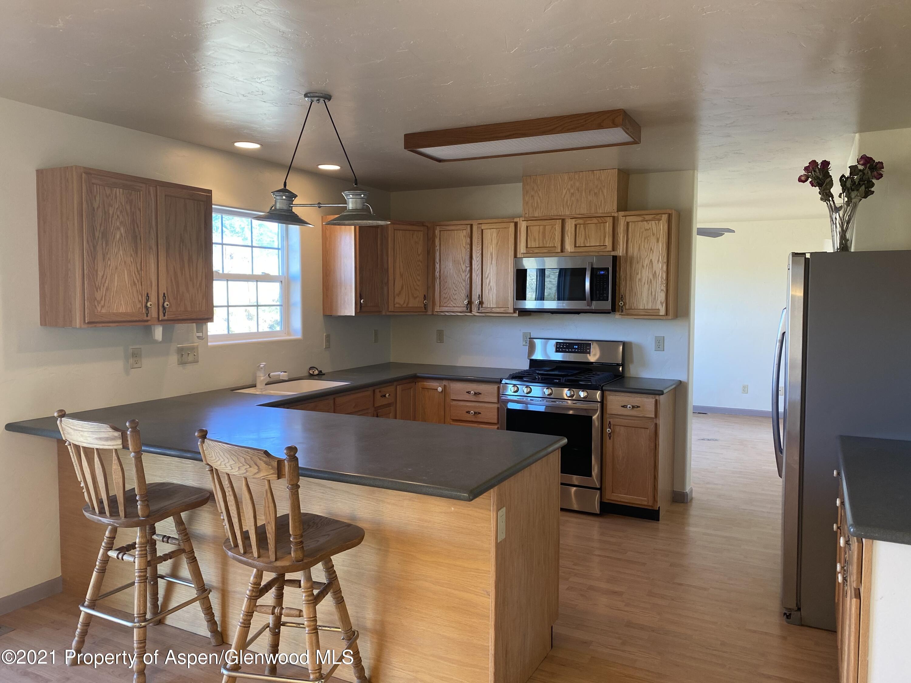 658 Cindys Way Rifle, CO 81650 - Photo 3 of 30 a kitchen with granite countertop a stove top oven a sink dishwasher a dining table and chairs with wooden floor