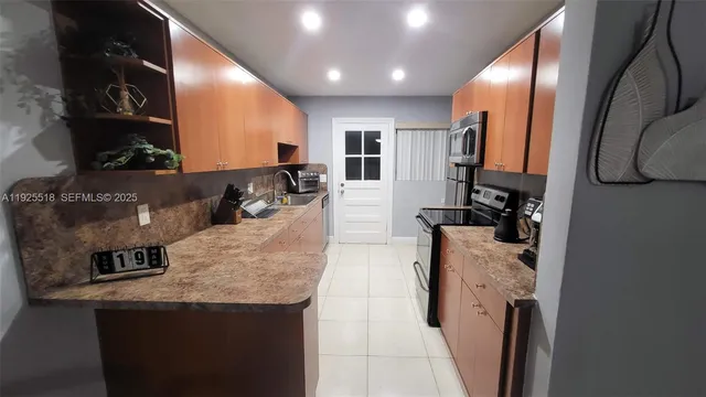 a living room with stainless steel appliances furniture a rug and a view of kitchen