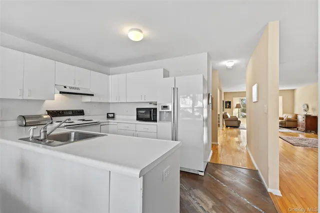 a kitchen with a refrigerator a stove top oven and white cabinets