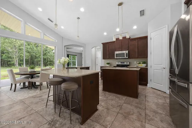 a kitchen with kitchen island granite countertop a stove refrigerator a sink a oven with a dining table and chairs