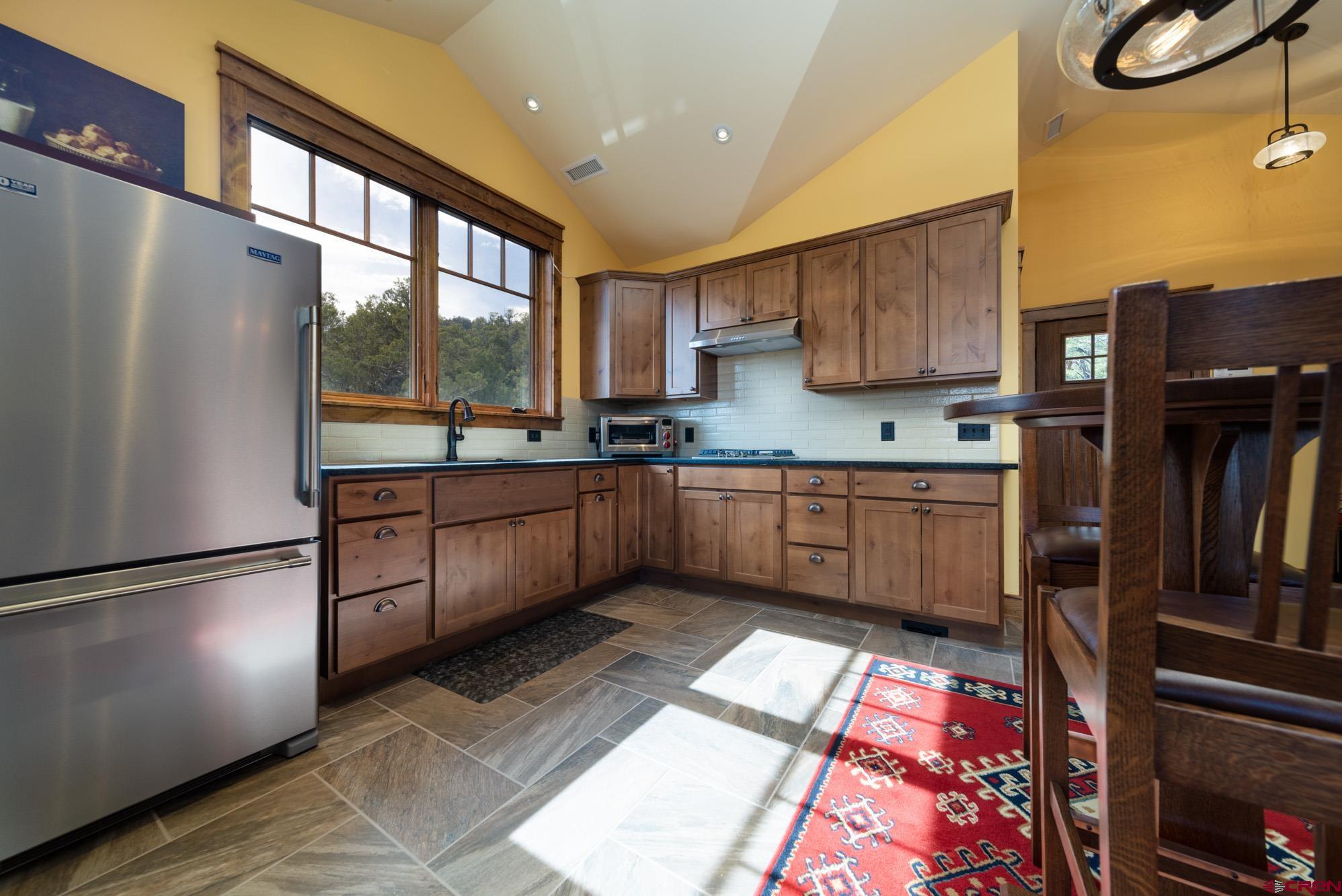 6534 Pleasant Point Drive Ridgway, CO 81432 - Photo 29 of 35 a kitchen with stainless steel appliances granite countertop a refrigerator a sink dishwasher a stove and a dining table with wooden floor