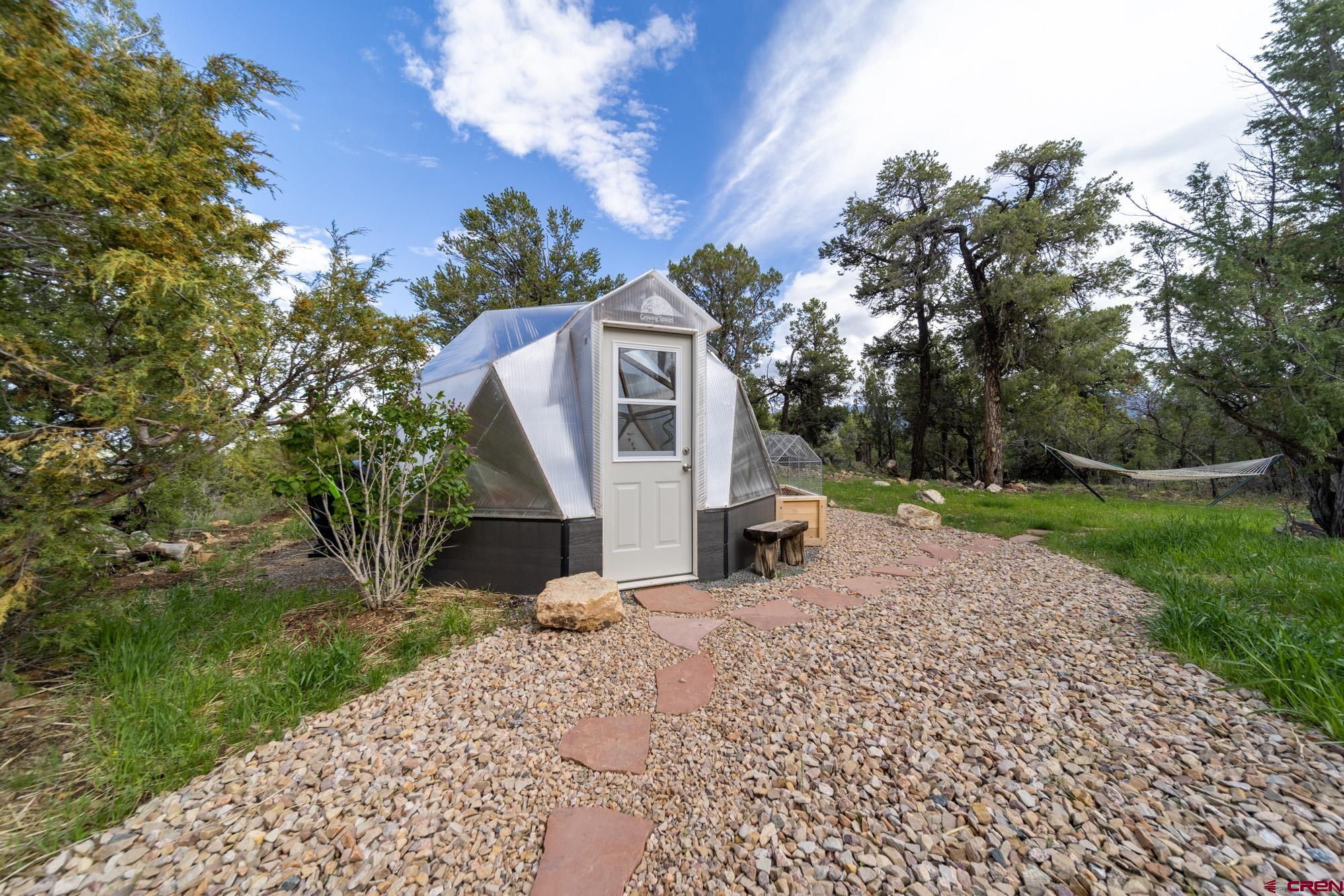 6534 Pleasant Point Drive Ridgway, CO 81432 - Photo 32 of 35 a view of a grey house with a yard and large trees