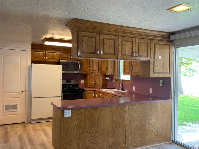 438 East Main Street Elsinore, UT 84724 - Photo 16 of 43 Kitchen featuring wood-finish cabinetry, stainless steel microwave, black gas range, and light wood-finish flooring