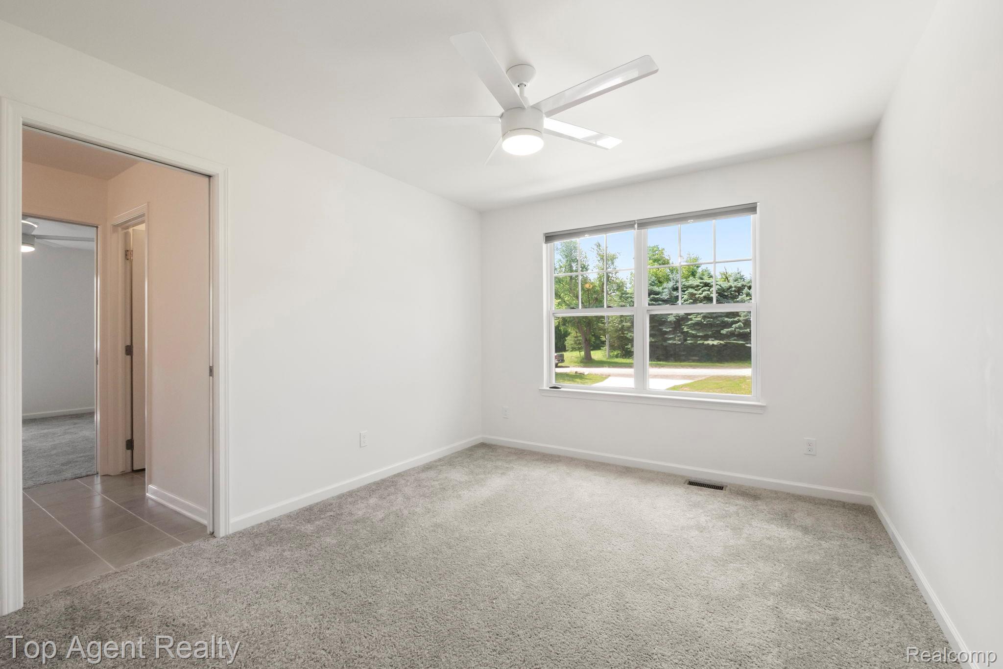 63770 Dequindre Road Washington, MI 48095 - Photo 33 of 61 Carpeted room featuring a large window, white trim, and a ceiling fan with integrated lighting