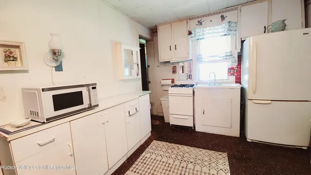 a living room with furniture a flat screen tv and a refrigerator
