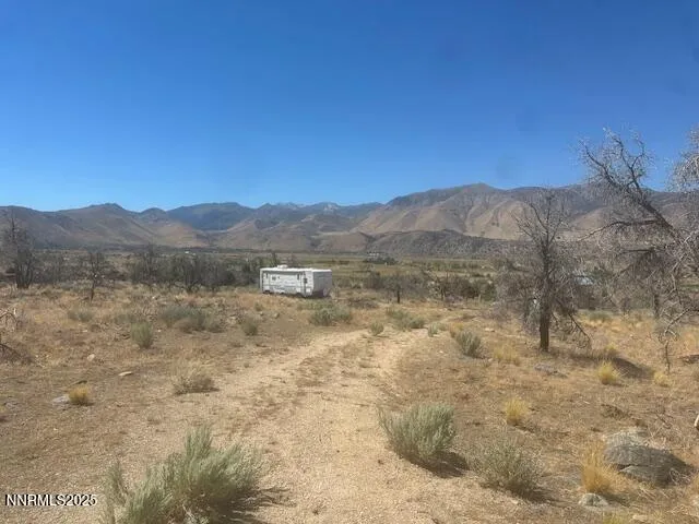 a view of a dry yard with mountains in the background