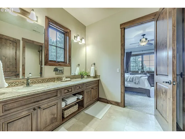 a bathroom with a granite countertop double vanity sink a mirror and a bathtub