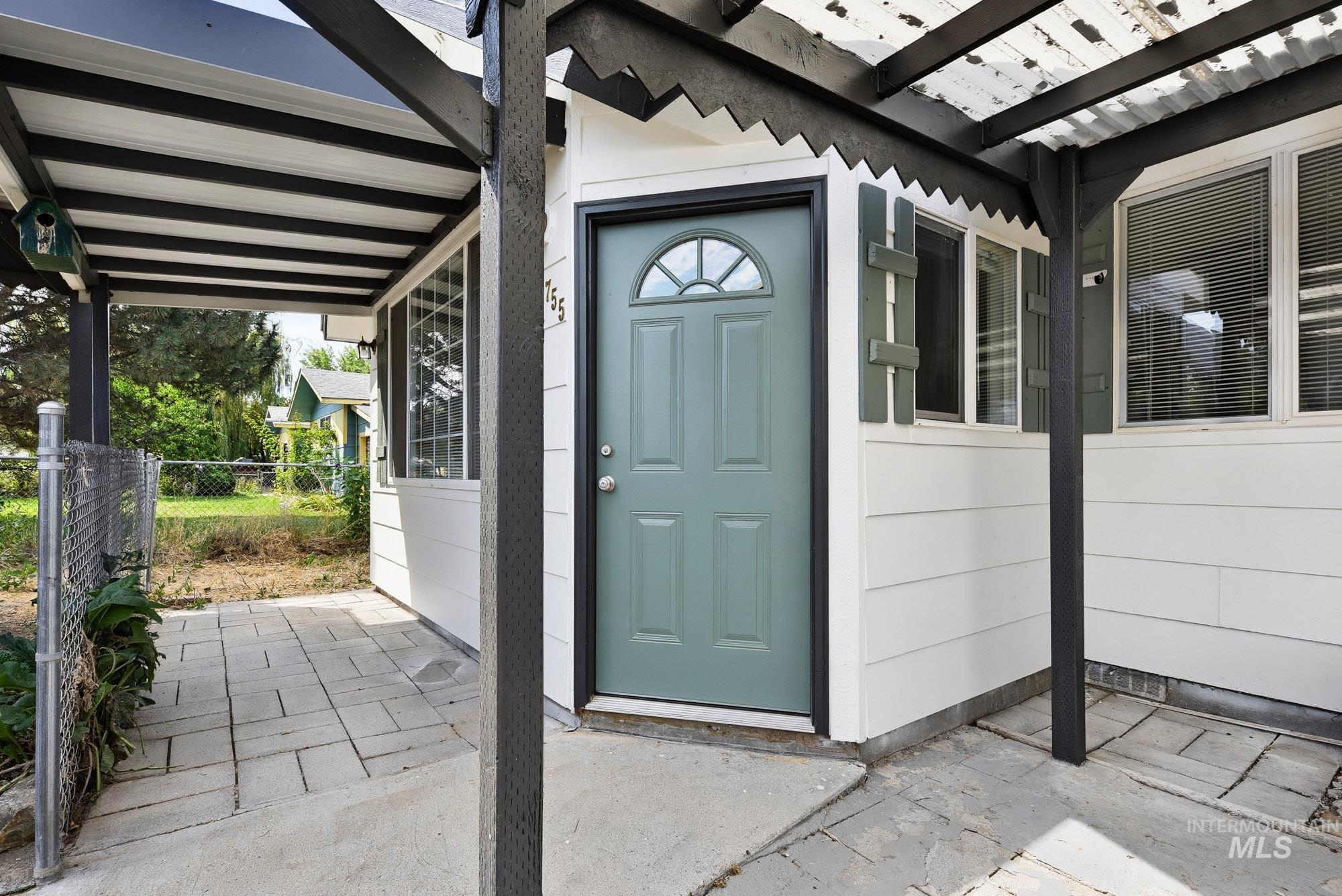 5755 Chuckwagon Road Nampa, ID 83686 - Photo 4 of 50 White siding exterior with a paneled entry door, arched transom window, decorative shutters, and a covered entry with a paver patio