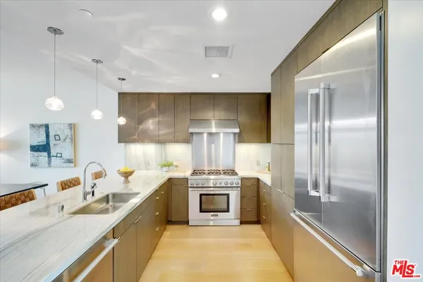 a modern kitchen with stainless steel appliances granite countertop a sink and a refrigerator