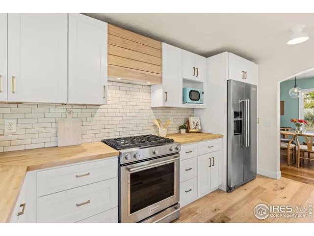 a kitchen with stainless steel appliances granite countertop a stove a refrigerator and a white cabinets