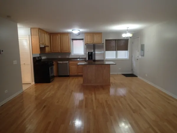 a kitchen with stainless steel appliances kitchen island granite countertop a stove a refrigerator a sink a microwave oven with wooden floor and cabinets