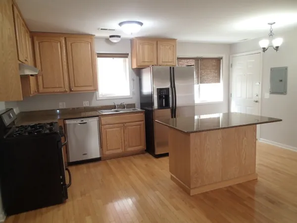 a kitchen with stainless steel appliances granite countertop a sink a stove a refrigerator and island with wooden floor