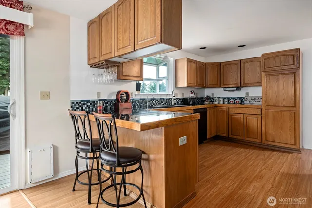 a kitchen with stainless steel appliances granite countertop wooden cabinets a sink a stove a dining table and chairs