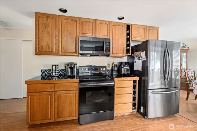 a kitchen with stainless steel appliances granite countertop a stove a sink dishwasher and cabinets with wooden floor