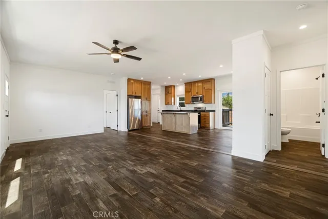 a view of empty room with wooden floor and kitchen view