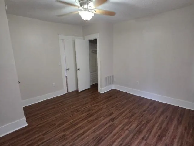 a view of an empty room with wooden floor and a window
