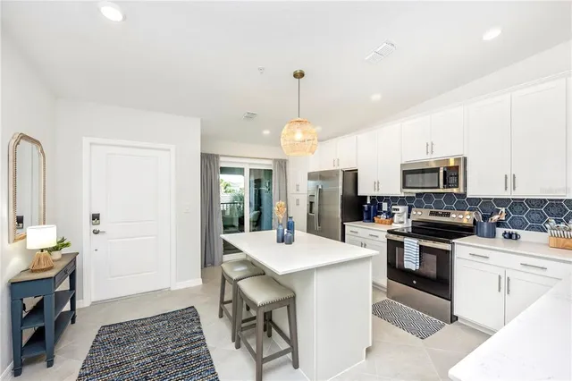 a large white kitchen with a refrigerator a sink and a large window