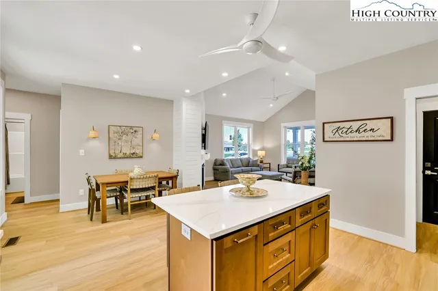 a living room with stainless steel appliances kitchen island a table and chairs in it