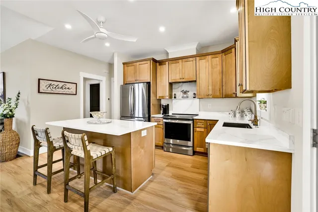 a kitchen with a refrigerator a stove a sink dishwasher and white cabinets with wooden floor