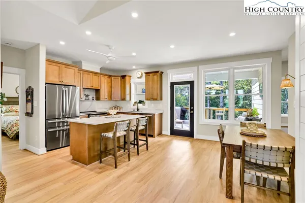 a kitchen with stainless steel appliances granite countertop a stove a refrigerator a sink a dining table and chairs with wooden floor