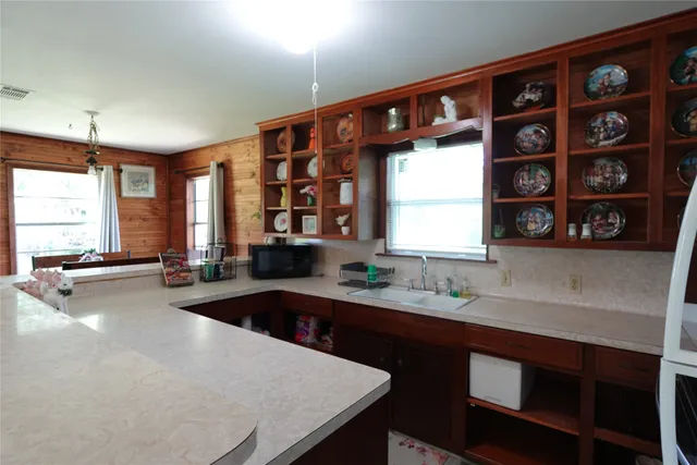 a kitchen with a sink a window and chairs
