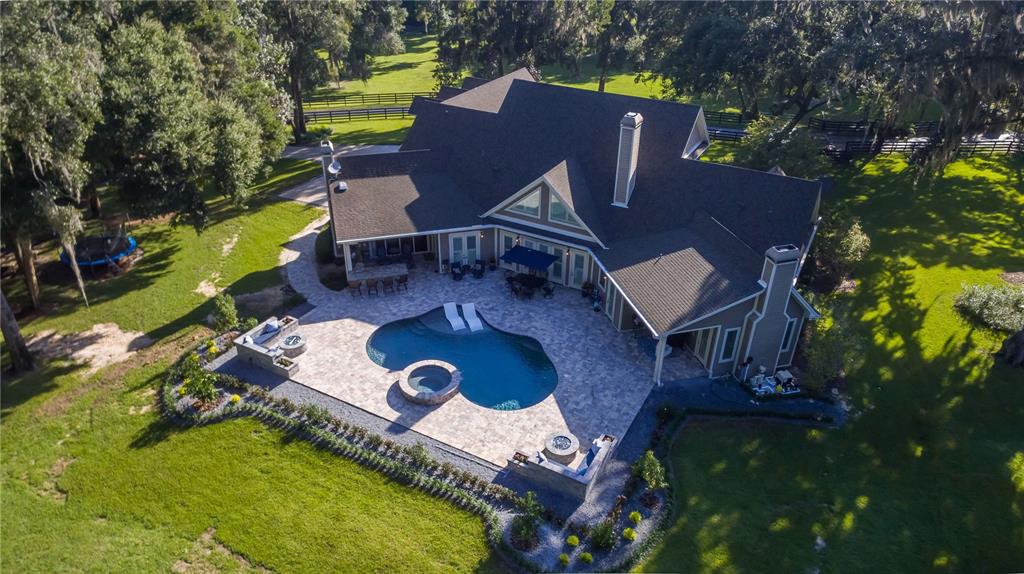an aerial view of a house with swimming pool a yard and outdoor seating