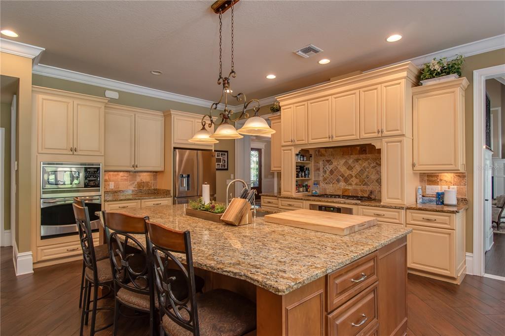 1219 Southwest 63rd Street Road Ocala, FL 34476 - Photo 27 of 72 a kitchen with granite countertop a table chairs stove and cabinets