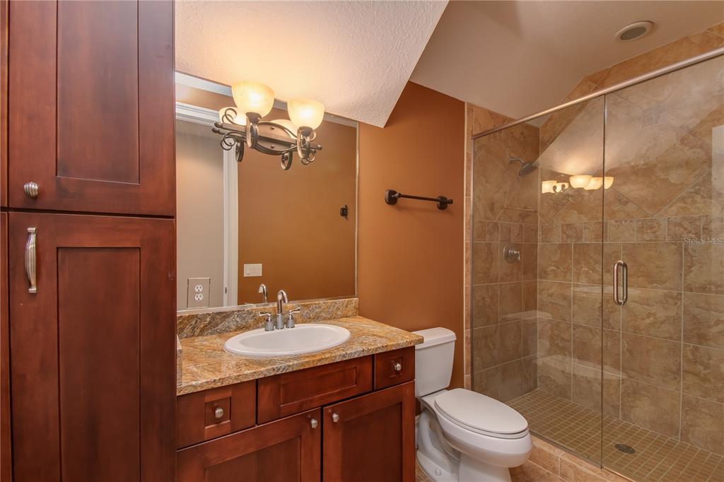 1219 Southwest 63rd Street Road Ocala, FL 34476 - Photo 46 of 72 a bathroom with a granite countertop sink toilet a mirror and shower