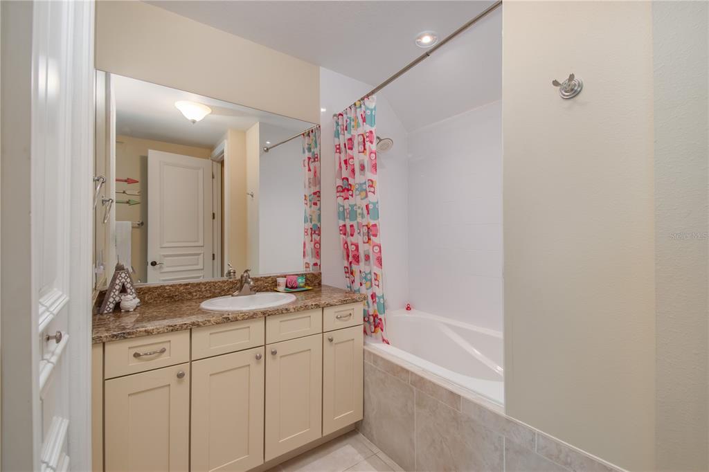 1219 Southwest 63rd Street Road Ocala, FL 34476 - Photo 49 of 72 a bathroom with a granite countertop sink a mirror a vanity and a bathtub