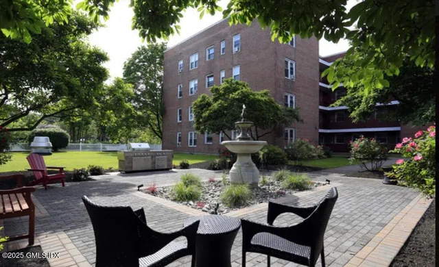 a view of a patio with table and chairs potted plants and a large tree