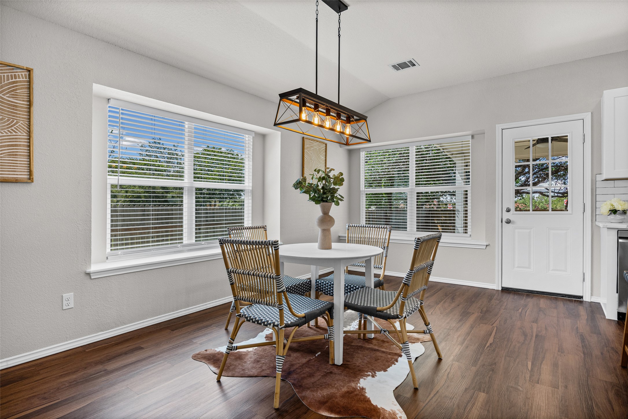 1524 Lochaline Loop Pflugerville, TX 78660 - Photo 8 of 22 A cozy dining area features rich wood flooring, framed by large windows, and illuminated by a modern chandelier.