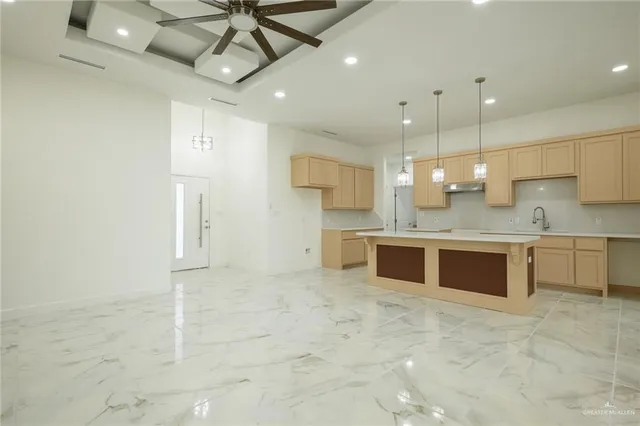 a large kitchen with a large counter top a stove a sink and a refrigerator