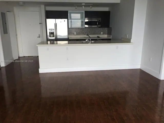 a view of kitchen with stainless steel appliances wooden floor and window