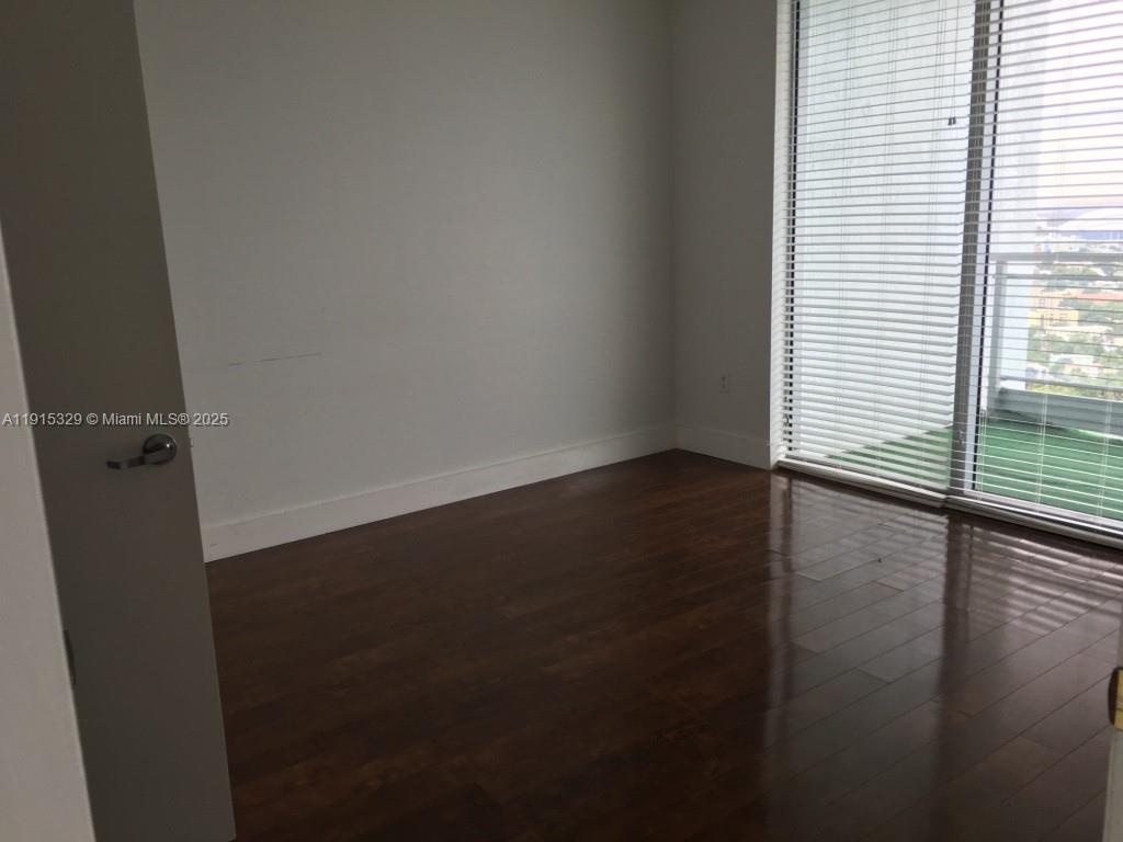 90 Southwest 3rd Street, Unit 3608 Miami, FL 33130 - Photo 10 of 12 an empty room with wooden floor and windows with curtains
