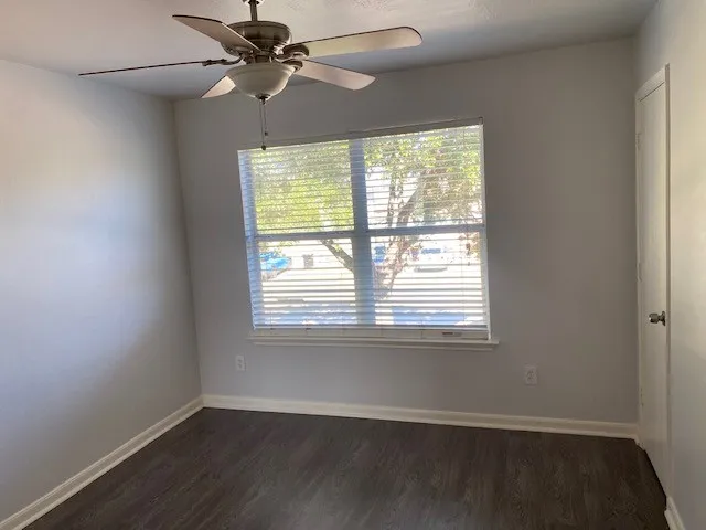 a view of an empty room with wooden floor and a window