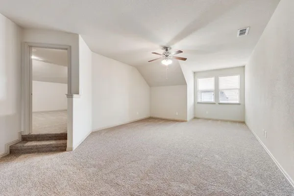 an empty room with chandelier fan and windows