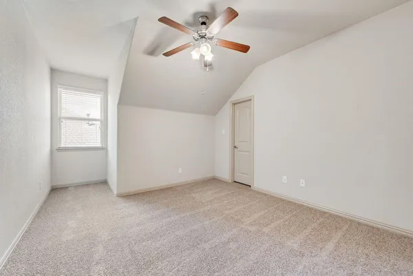 an empty room with chandelier fan and windows