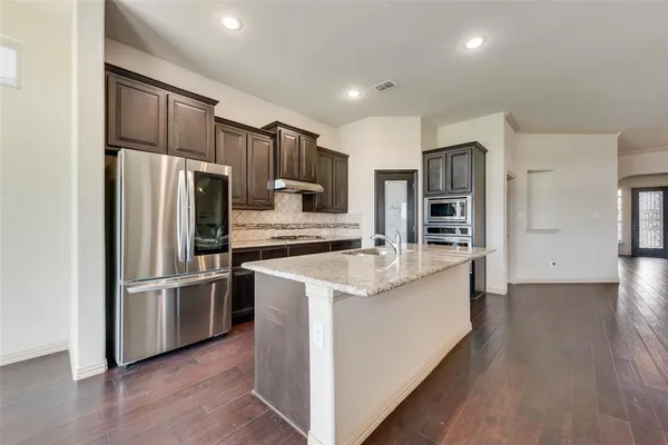 a kitchen with stainless steel appliances granite countertop a refrigerator and a stove top oven