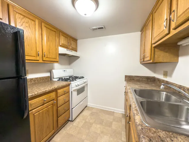 a kitchen with granite countertop a sink a stove and refrigerator