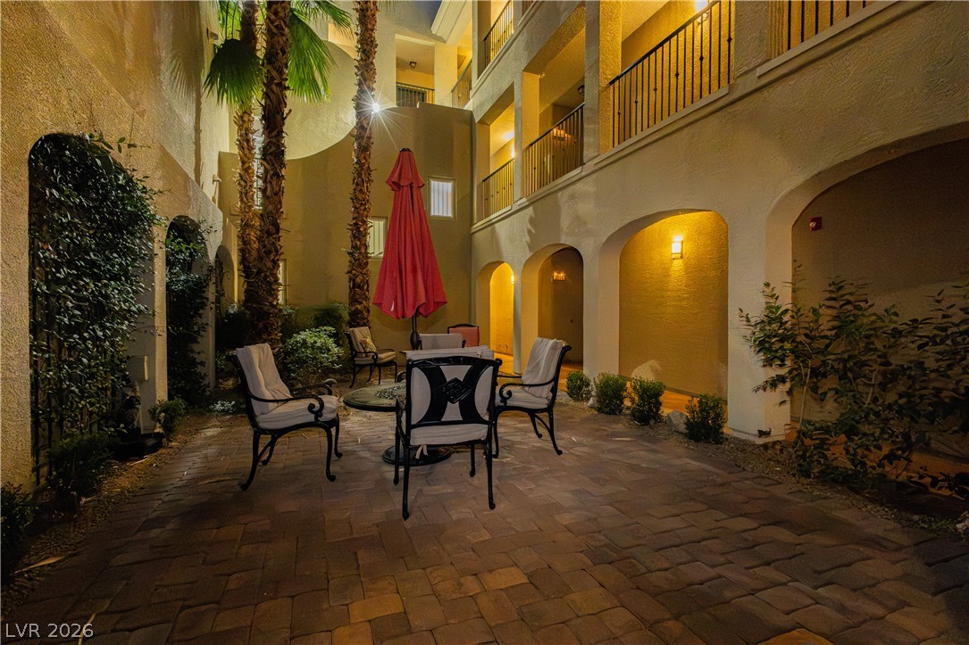 2555 Hampton Road, Unit 3308 Henderson, NV 89052 - Photo 42 of 65 An inviting courtyard beckons with arched passageways and mature palm trees under warm evening lights.
