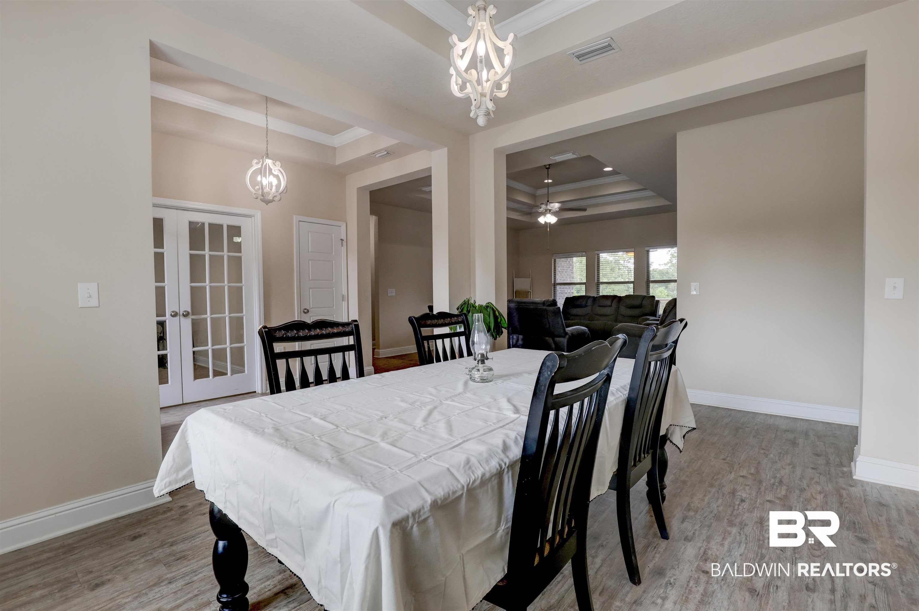 21902 Yosemite Boulevard Fairhope, AL 36532 - Photo 4 of 32 Dining area with a raised ceiling, french doors, ceiling fan with notable chandelier, crown molding, and hardwood / wood-style floors