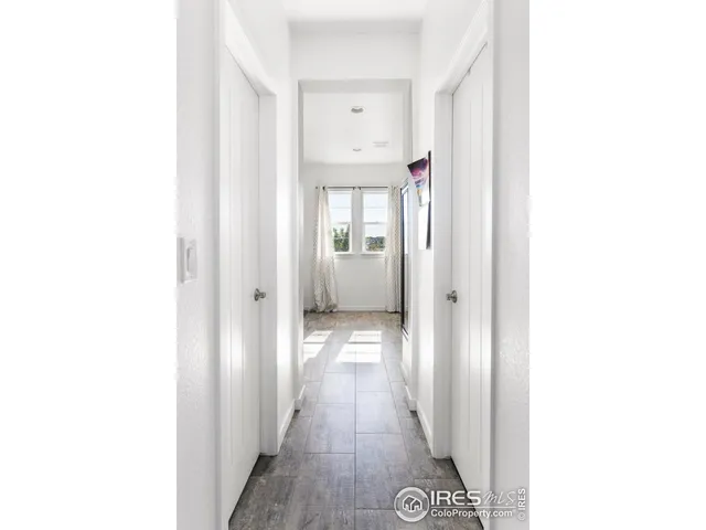 a view of a hallway with wooden floor and a bathroom