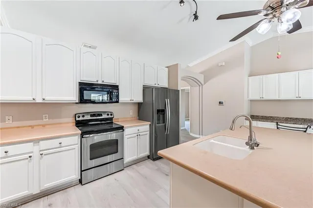 a kitchen with stainless steel appliances a sink a stove a refrigerator cabinets and a window