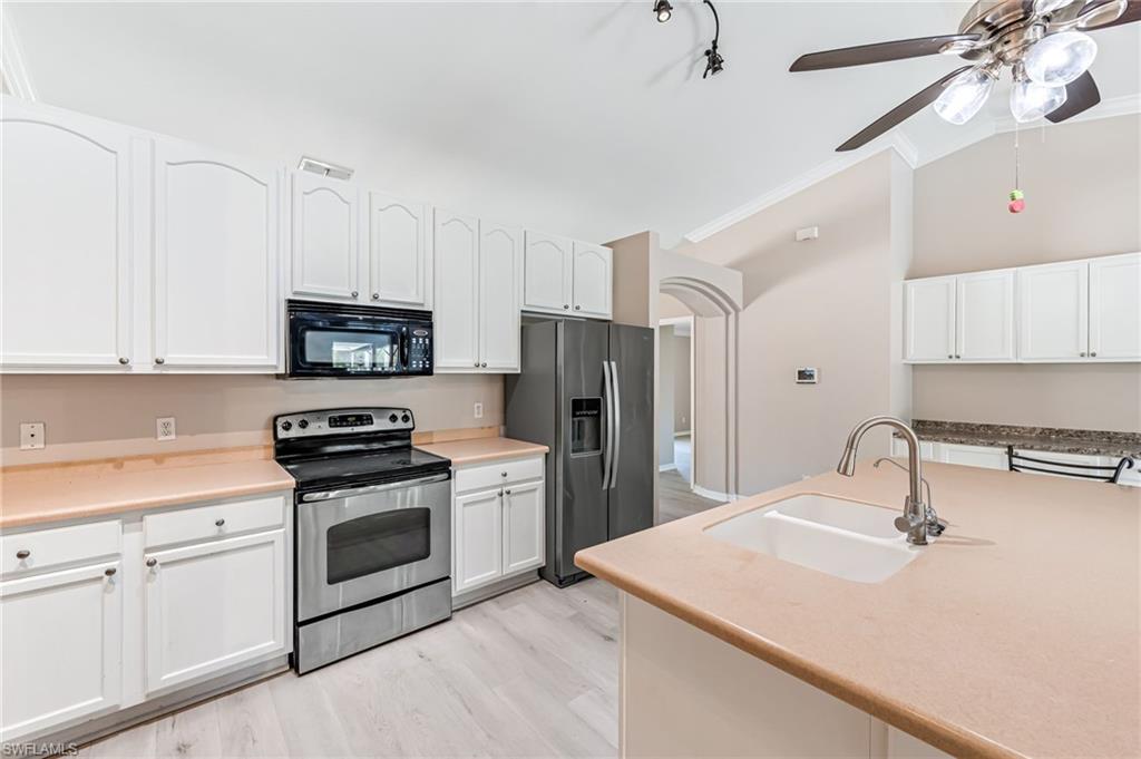3630 10th Avenue Southeast Naples, FL 34117 - Photo 14 of 50 a kitchen with stainless steel appliances a sink a stove a refrigerator cabinets and a window