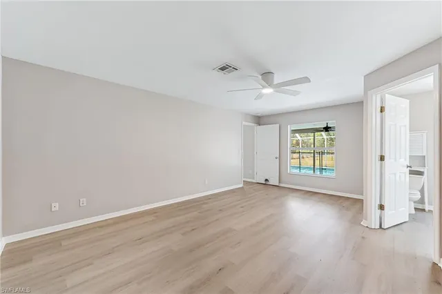 an empty room with windows and ceiling fan