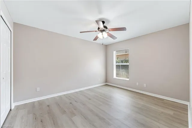 an empty room with wooden floor fan and windows
