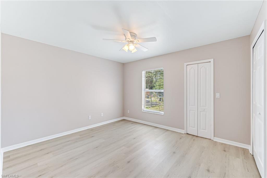 3630 10th Avenue Southeast Naples, FL 34117 - Photo 33 of 50 an empty room with wooden floor ceiling fan and windows